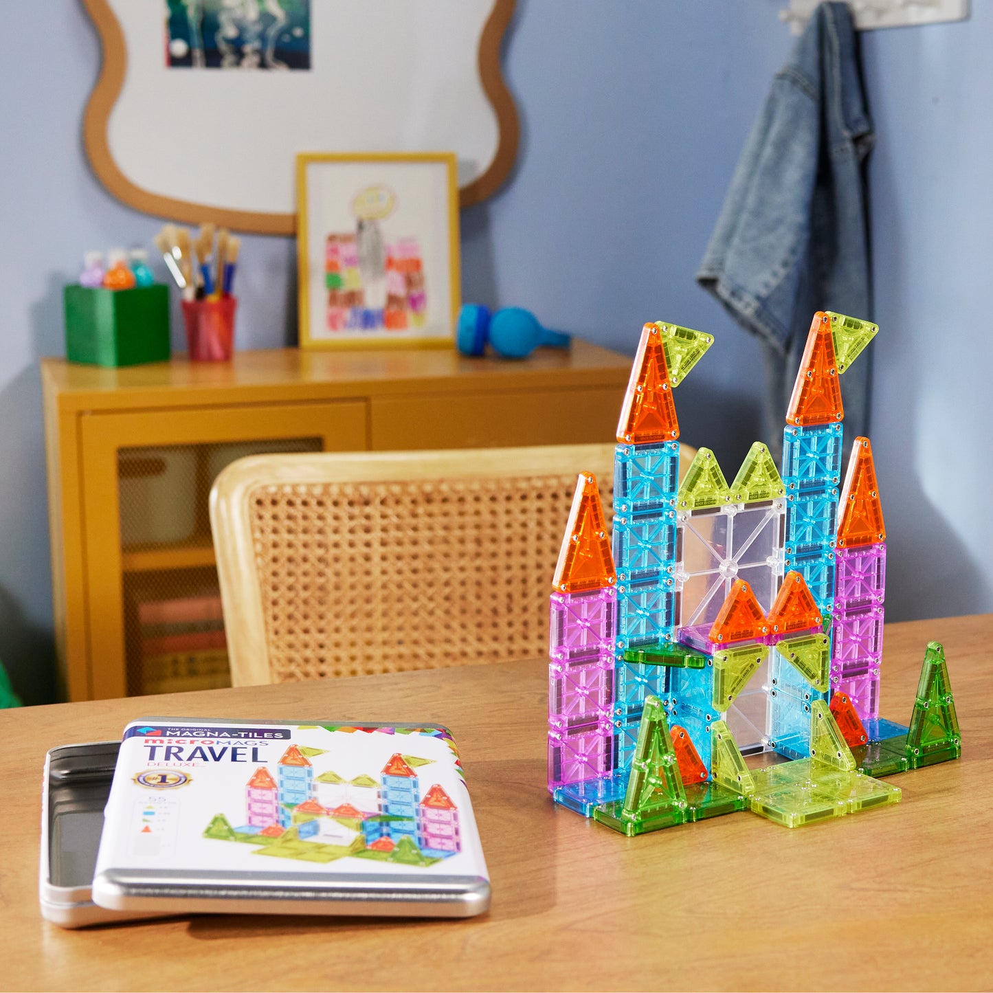 Colorful magnetic building blocks on a table with a book titled 'Travel' in a room setting.