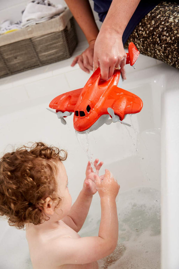 Adult pouring water from a Green Toys Fire Plane during a child's bath